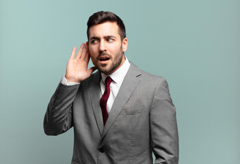 young adult handsome businessman looking serious and curious, listening, trying to hear a secret...