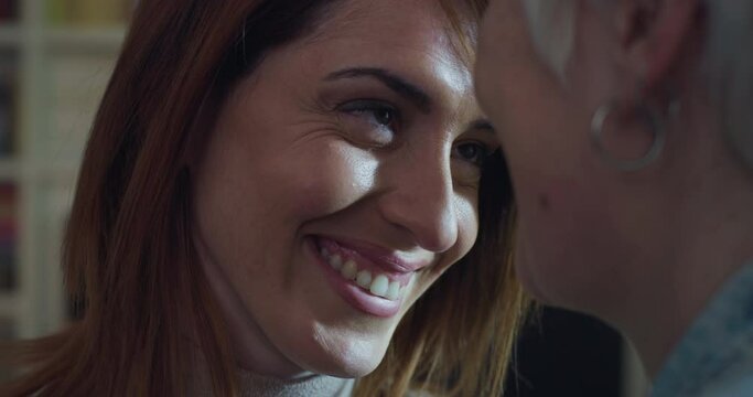 Cinematic close up of carefree happy homosexual female gay and transgender man couple in love is enjoying time together is hugging and kissing with affection as sign of timeless forever love at home.