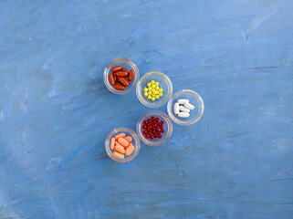 5 types of types of vitamins. Colorful capsules on a blue background