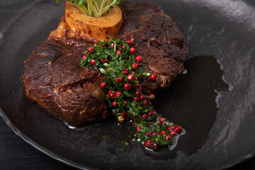 Venison chop with micro greens and sauce on a black plate