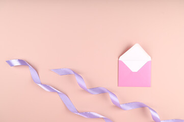 Pink paper envelope with blank white note mockup inside, violet ribbons on pastel background