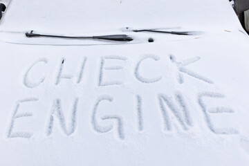 the inscription on the hood of a frozen broken car covered with snow, parked outside on a frosty winter day. the engine does not start