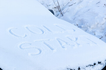 the inscription on the hood of a frozen broken car covered with snow, parked outside on a frosty winter day. the engine does not start