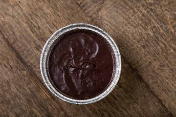 Melted milk chocolate in foil pot on a wooden table