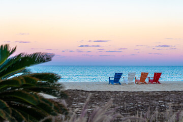 Beautiful colourful sunset and chairs on the beach of the turquoise Mediterranean sea at El Alamein...