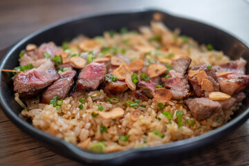 Beef with garlic fried rice, a Japanese dish consisting of a bowl of rice topped with rare beef served on a black pan