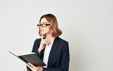Business woman in a blue jacket and a white shirt with glasses on her face and a book in her hands