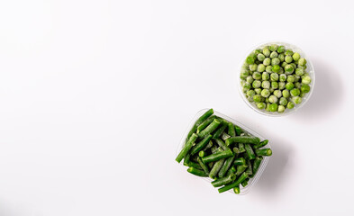Frozen green beans and peas in plastic box isolated on white background.