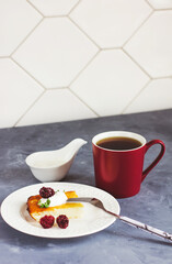 Cottage cheese casserole on a white plate and tea in a burgundy cup on a gray background