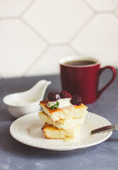 Cottage cheese casserole on a white plate and tea in a burgundy cup on a gray background