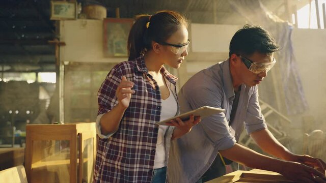 Asian carpenter and design team are check quality the wood specification in furniture design in the factory. Wearing safety Mechanic Mask while working. Product quality inspection service. 