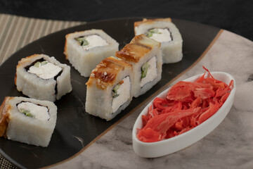 Dragon sushi rolls with eel and pickled ginger on marble plate
