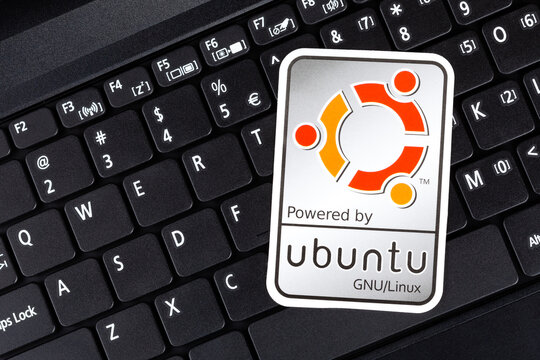 Powered by Ubuntu GNU Linux operating system sticker, logo symbol label closeup, laptop keyboard. Debian open source software technology concept, top view