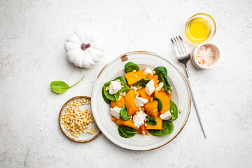 Salad with roasted pumpkin, cheese, spinach, Pine nuts and seasonings on white background, top view