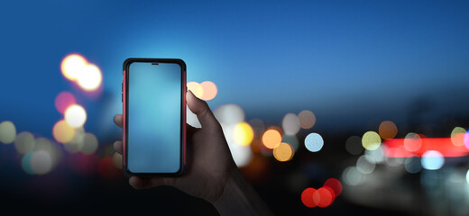 woman using the cell phone in the city at night - mobile payment or texting. Display empty. 