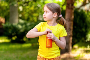 School age young child, happy little girl opening a glass bottle full of healthy orange carrot juice, simple outside outdoors portrait closeup, nature, copy space Healthy active kids lifestyle concept