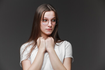 attractive surprised excited scared, terrified teenage girl wear glasses, white t shirt, with brown long hair, isolated on gray background. Concept of human emotions, facial expression, sales, ad.