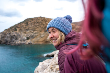 Portrait of a smiling girl in a knitted hat while walking along the sea coast