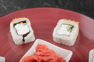 Delicious dragon sushi rolls with eel and pickled ginger on red plate