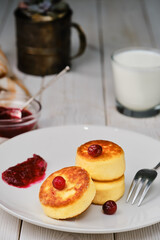 Fried curd pancakes - cheese pancakes on a plate. Healthy breakfast cheese pancakes traditional breakfast of Ukrainian and Russian cuisine, close-up, selective focus, white wooden table