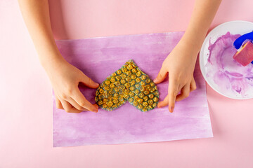 Obraz premium DIY and kids creativity Step by step instruction: Drawing greeting card non-standard method. Step2 apply gold paint to heart-shaped bubble wrap. Valentines, womens and mothers day craft.
