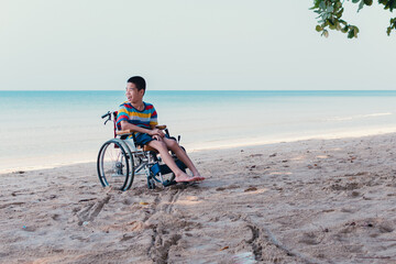 Obraz premium Asian special child on wheelchair is fun, playing ball and exercise activity on sea beach at summer, Lifestyle of disability child, Life in the education age, Happy disabled kid in travel concept.