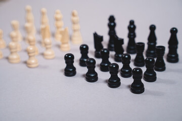 white and black chess pieces stand opposite each other on a gray background