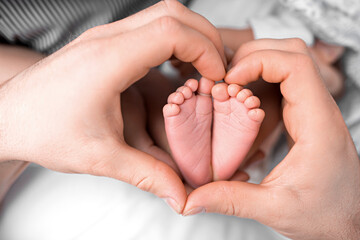 Feet of the newborn in the hands of mom close up. Heart. Mom and her child. A beautiful conceptual image of motherhood.