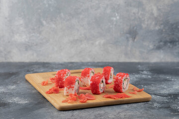 California sushi rolls and pickled ginger scattered on wooden board