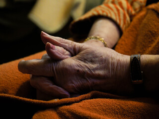 hands of an old woman sit down on a sofa