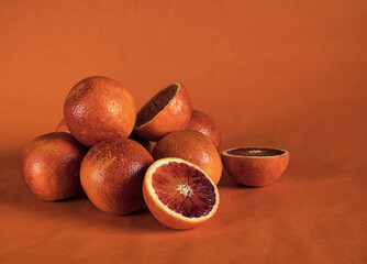 Ripe juicy whole and cut blood  oranges on orange background.Rustic food photography, Still life.