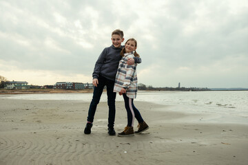 Portrait of two happy teenager siblings children walking and having fun on Baltic sea beach