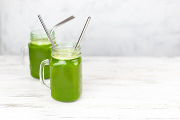 Two glasses filled with herb green detox smoothie with straws