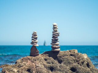 Zen stone pyramid by the mediterranean sea with sailboat at the bottom