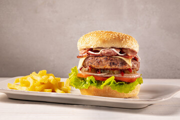 Close-up home made beef burger and fries on wooden board, clear light background
