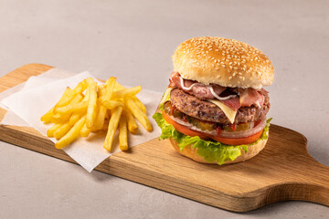Close-up home made beef burger and fries on wooden board, clear light background