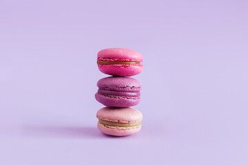 Tasty french macarons on a violet pastel background. Pink and violet macarons.
