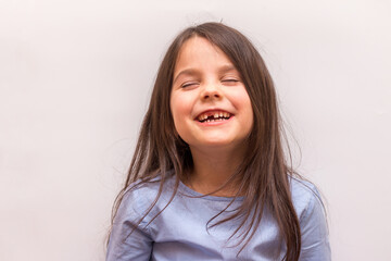 Smiling hispanic little girl with no front tooth on white studio background
