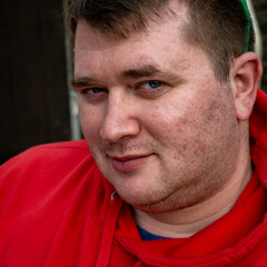 A close-up portrait of a young man with blue eyes.
