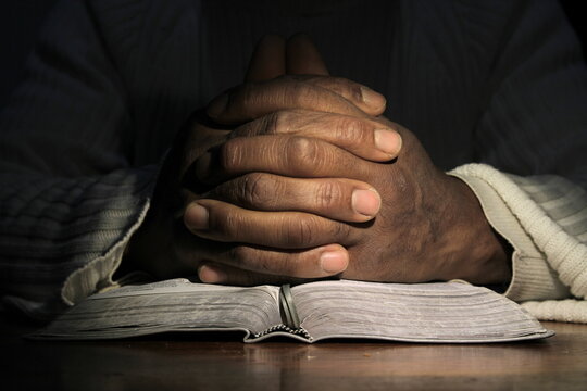 man praying with bible with black background with people stock image stock photo