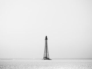 View to old lighthouse in frozen water in vintage style under clear sky in winter day