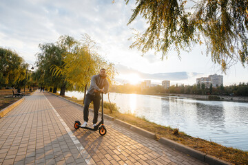 A young guy rides in the Park on an electric scooter on a warm autumn day. Walk in the Park.