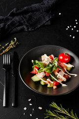 salad with vegetables in a plate on a black textured background
