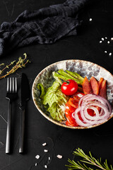 salad with vegetables in a plate on a black textured background