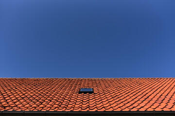 Naklejka premium tile roof of house with window attic against the blue sky