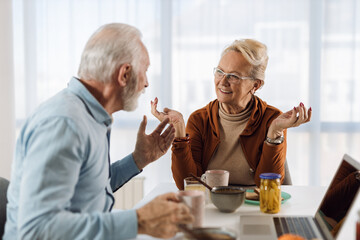 Happy mature couple communicating while having breakfast at dining table