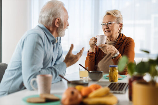 Happy Mature Couple Communicating While Having Breakfast At Dining Table