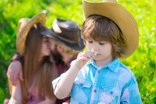 Gardener family on picnic outdoor. Summertime parent with kid in garden or park. Parenthood together leisure concept. Vife husband kiss.