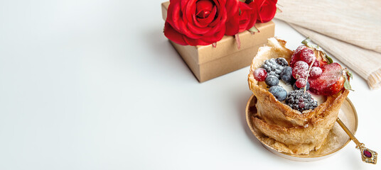 French dessert from bakery on white table with gift box and red roses on background