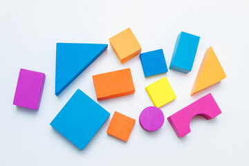 Colorful blocks of children's designer of various geometric shapes on white background close-up, concept of children's play, creativity and development of fine motor skills, classes for intelligence